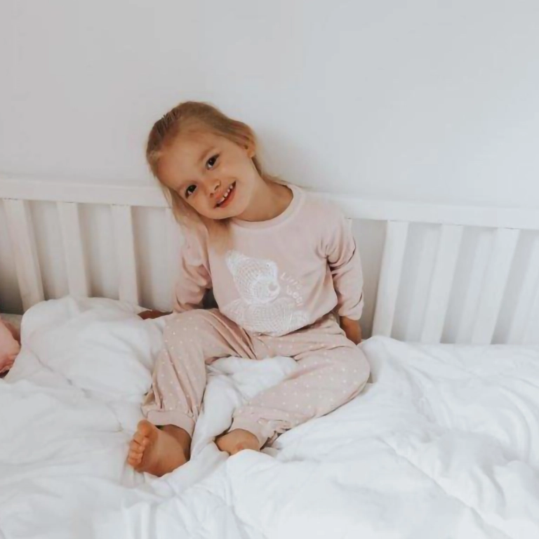 Dziewczynka w piżamie siedząca na łóżku